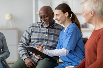 Fototapeta premium Focused Young Female Nurse Discussing Health Plan With Male Patient In Clinic Setting, Engaged In Consultation. Group Of Three Adults In A Friendly And Supportive Environment, Healthcare Concept.