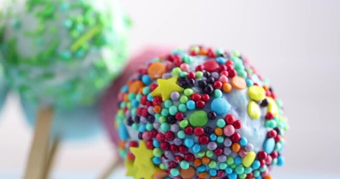 Tasty cake pops on blurred background, closeup. Camera moving right