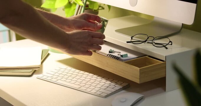 Woman taking highlighter from drawer of under monitor riser at desk indoors, closeup