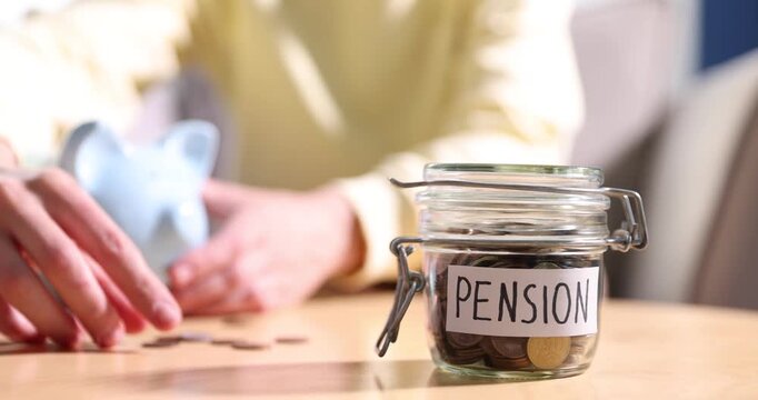 Jar with word Pension and coins on table, man putting money into piggybank indoors, selective focus
