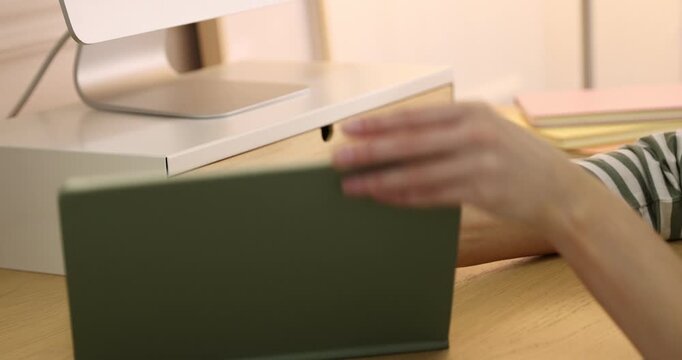 Woman putting pencil into drawer of under monitor riser at wooden desk indoors, closeup