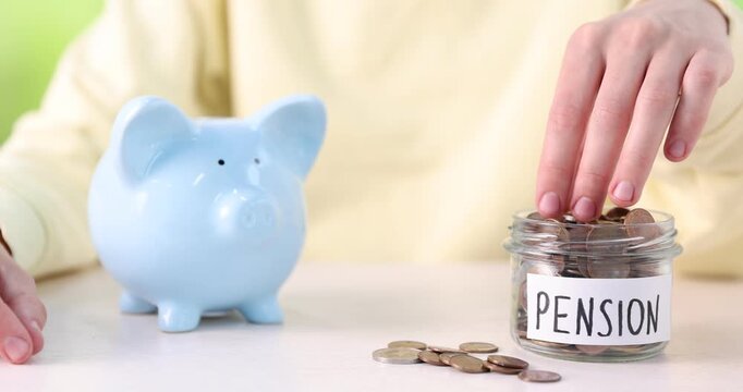 Man putting money from jar with word Pension into piggy bank at white table, closeup