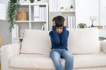 Fototapeta premium Mental health, Unhappy asian boy holding head with hands showing sad expression, Concept of child health problem, headache pain, emotional stress, childhood frustration and psychological care support