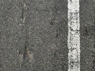 Fototapeta premium Close-up of weathered asphalt road surface with a white line marking