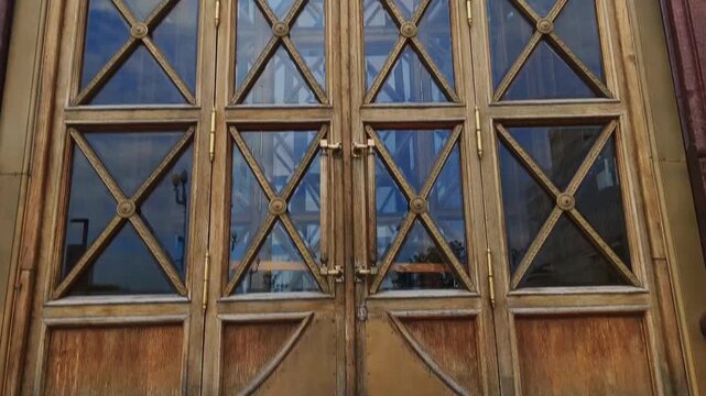 Detail of an old building style wooden brown door with glass. Aged gate art construction in the city center	

