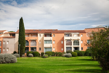 Fototapeta premium Holiday residence on the French Riviera, with pastel apartment buildings, terracotta roofs, balconies, cypress tree, gardens and lawns showing Mediterranean real estate and vacation housing in france.