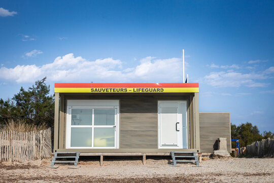 French lifeguard office on a Mediterranean beach in Hyeres, with a Sauveteurs Sign, meaning Lifeguard in french, sand fencing, clear blue sky, gravelly sand and a rescue hut on the French Riviera.