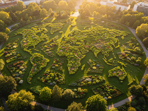 A city park planted as a living world map of continents from above &mdash; Earth Day as a garden of nations. Ideal for Earth Day, environmental brands, green urban planning, and ecology editorial.