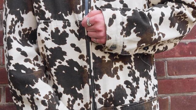 Video close up of someone zipping their jacket up.