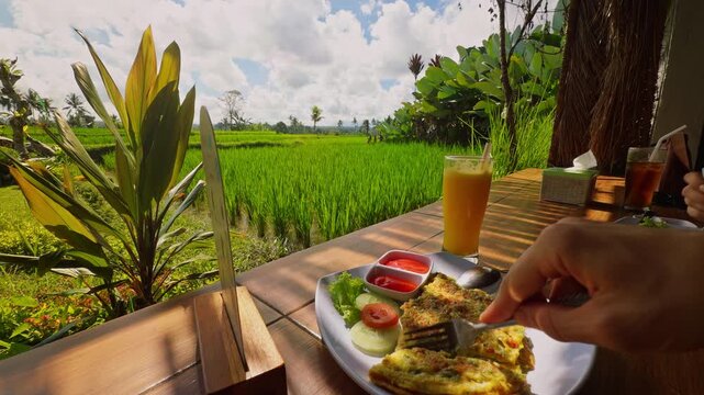 First Person Breakfast at Open Air Cafe Overlooking Green Rice Fields, Fresh Tropical Meal And Juice Served Beside Scenic Agricultural Landscape