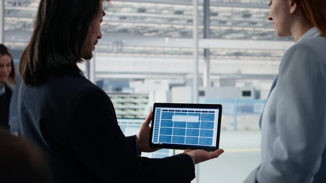 Senior manager doing microchips yield enhancement with worker using tablet, tracking defects data, teamwork colleagues use device app to monitor PCB production dashboard in officecloseup.