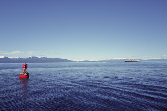 Alaskan seals rest on an ocean buoy as a cruise ship passes through the waters by Icy Straits, Alaska