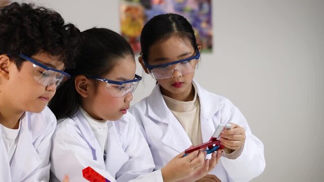 Asian Children in Lab Coats Conducting Science Experiment with Magnets