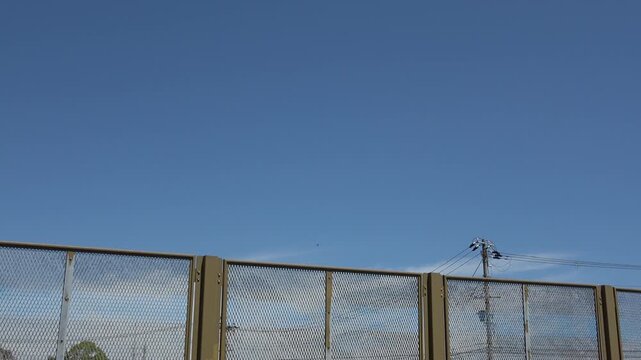 快晴の青空と金網フェンス・電柱の背景素材