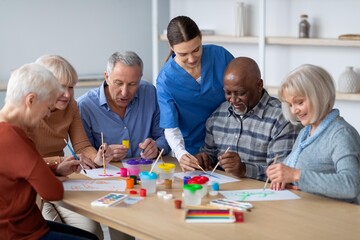 Fototapeta premium Joyful Seniors, Including Caucasian And African American Individuals, Actively Participating In Art Therapy Activities With A Nurse At A Community Center, Promoting Engagement And Creativity