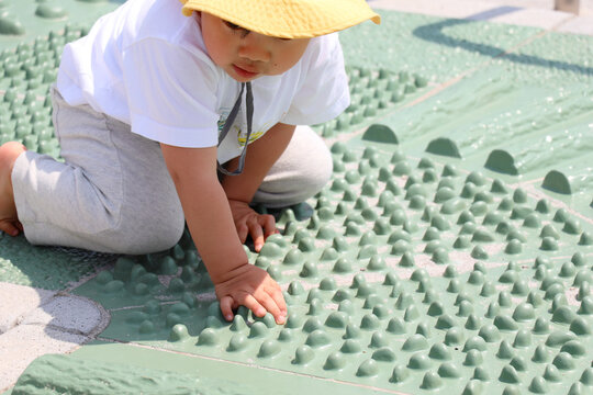 公園の健康遊具で裸足になって遊ぶ幼児の姿。足裏への刺激や触覚体験、子どもの感覚遊びや発達をイメージした写真素材。