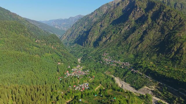 Grahan Village surrounded by dense pine forests, rugged Himalayan mountains and river valley near Sar Pass Trek and Sosan, Kasol, Himachal Pradesh, India. Panoramic aerial