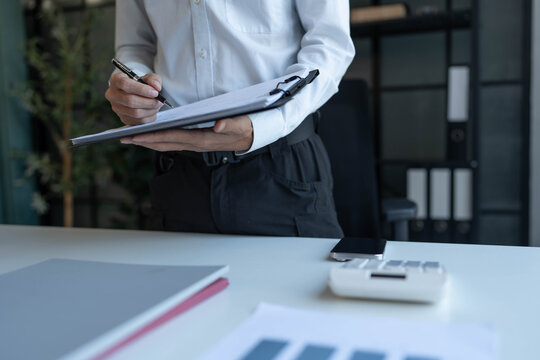 Businessman standing chekking documents with pen