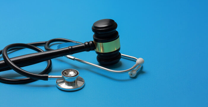 Solemn concept of ethical medicine law justice represented by black gavel and stethoscope on blue background depicting malpractice