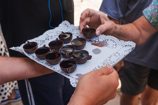 Crowd assembles for shots of traditional Portuguese sour morello cherries sweetened, spiced and marinated in aguardente liquor, Ginjinha, in chocolate cups