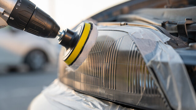 The process of polishing car headlights outdoors. 