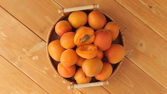 Ripe apricots in a basket rotating on a wooden table