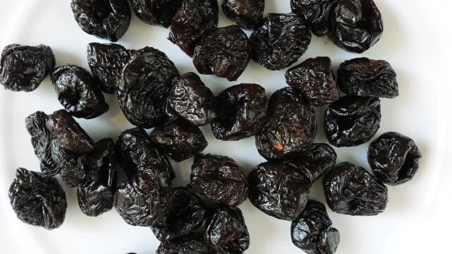 Healthy dried prunes rotating on a white background
