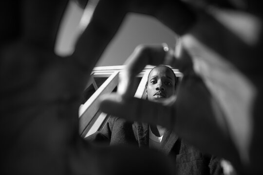Creative black man looking through hands frame with copy space