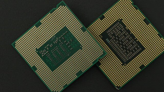 Two microprocessors are arranged on a dark surface, showcasing their intricate gold contact pins. Ideal for technology presentations or educational materials.