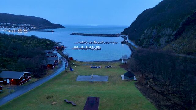 Beautiful 4K drone footage capturing active snow falling heavily over a scenic fishing village and harbour. Spectacular winter atmosphere in the remote fjords of Northern Norway.