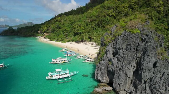 Aerial view of Seven Commandos Beach in El Nido Palawan Philippines with turquoise water limestone cliffs and traditional bangka boats