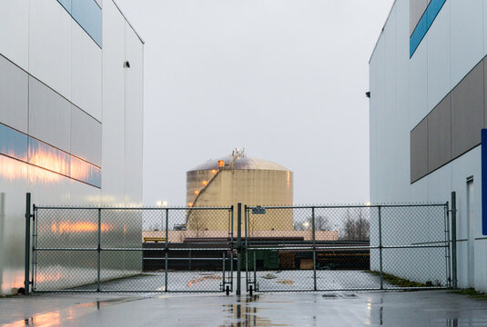 Canada, BC, Delta.  Liquified Natural Gas storage tank viewed between two warehouse buildings in the Tilbury Industrial Park.  