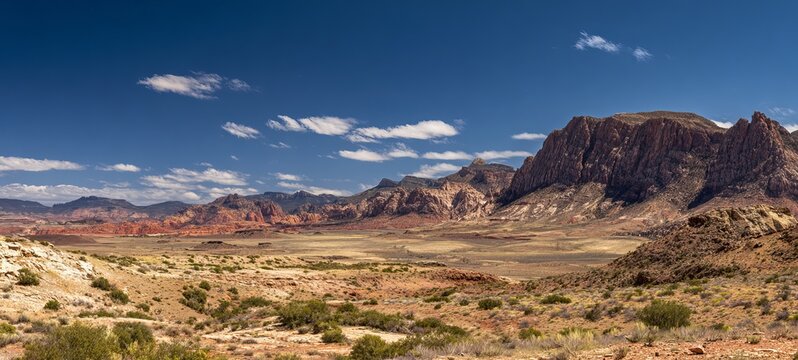 Vibrant desert landscape with mountains under a blue sky and clouds.