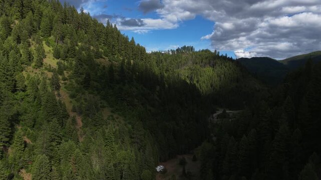 Aerial of dense forest and mountains in Shoshone County Idaho featuring deep green woods under a dramatic cloudy sky in spring in Coeur Dalene National Forest