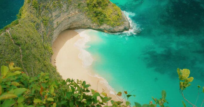 Tropical white sand cove surrounded by steep cliffs at Kelingking beach Bali Nusa Penida Indonesia