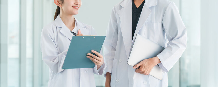 Male and female researchers, scientists, and research staff (pharmaceutical company, research institute) in white coats conversing and consulting with colleagues.
