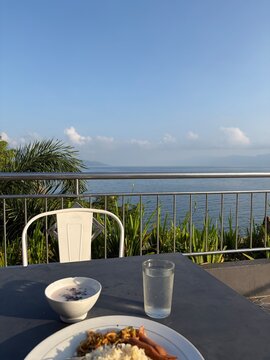 A beautiful resort breakfast setup featuring pastries, and ice water, overlooking a peaceful blue lake under a clear sky