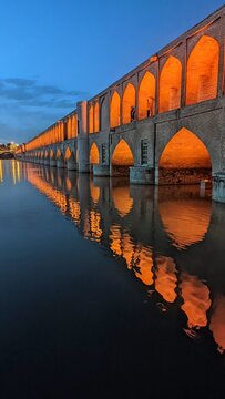 Khaju bridge over Zayandeh river at dusk with lights during blue hour. The Khaju Bridge is one of the historical bridges on the Zayanderud, the largest river of the Iranian Plateau, in Isfahan, Iran.