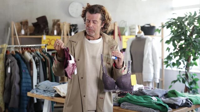 Seasonal trade sale, customer review at products in store and pick out clothes. Man search and choose bra, purchase some wardrobe items. Style and fashion type look, modern trends.