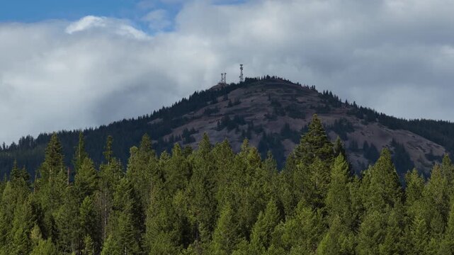 Aerial of mountain landscape and Wardner Peak in Shoshone County Idaho of dense evergreen forest and rolling hills under cloudy skies in spring near Kellogg
