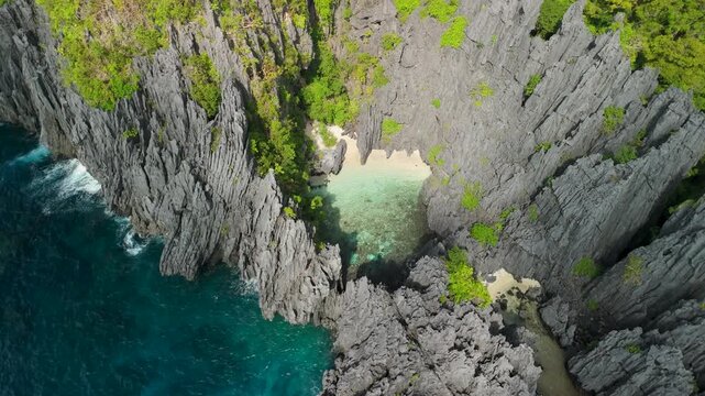 Aerial descent into Secret Beach El Nido a hidden sandy cove enclosed by towering limestone cliffs accessible only through narrow swimming crevice
