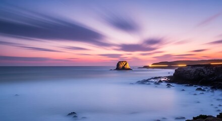 Obraz premium Stunning sunset over the ocean with a rocky island silhouette.