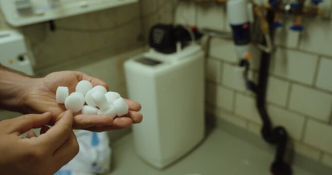 salt tablets used for refilling a water softener system in a utility room. Suitable for water treatment, descaling maintenance, limescale prevention, household technology, and plumbing service concept
