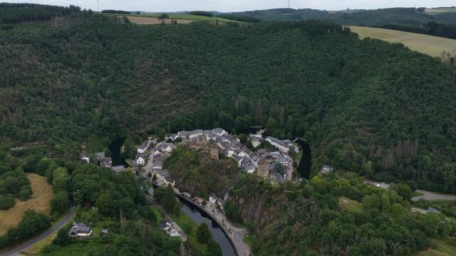 Stunning aerial footage showing the medieval village of esch sur sure in luxembourg. Situated on a narrow strip of land within a sharp meander of the sure river and surrounded by lush green forests