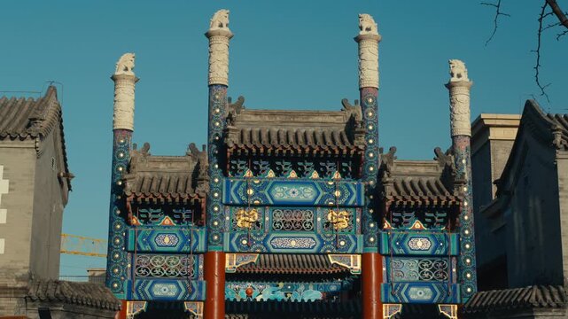 Beijing Traditional Paifang Archway with Intricate Blue and Gold Patterns and Stone Guardian Lions