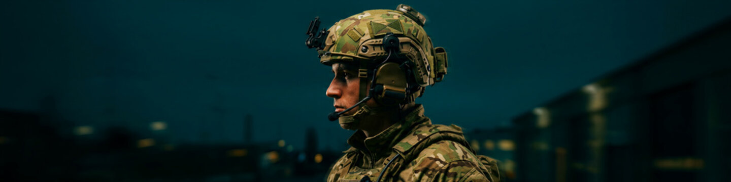 Soldier in camouflage helmet and tactical headset looking ahead. Special forces operator in gear at night. Military readiness concept, ideal for defense and tactical training marketing.