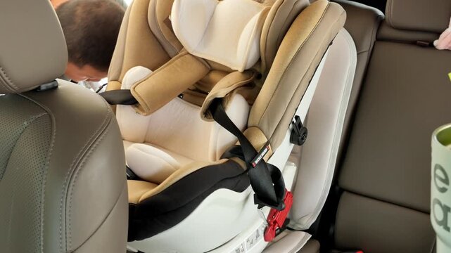 A man carefully secures an infant car seat in the backseat of a vehicle. Ideal for parenting guides or car safety tutorials.