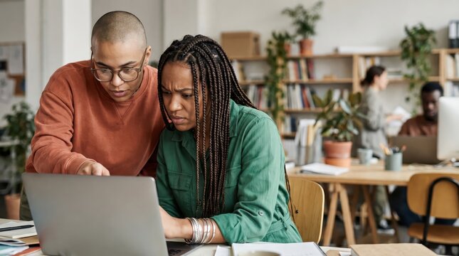 Generative AI, Two Black colleagues looking concerned while focused on laptop screen in creative office
