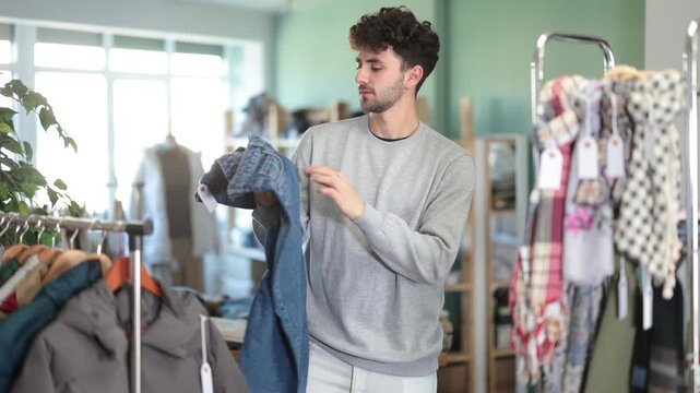 Undetermined young man looking for jeans pantaloons during shopping in retail outlet 