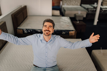 Fototapeta premium Man choosing mattress feeling comfort in store